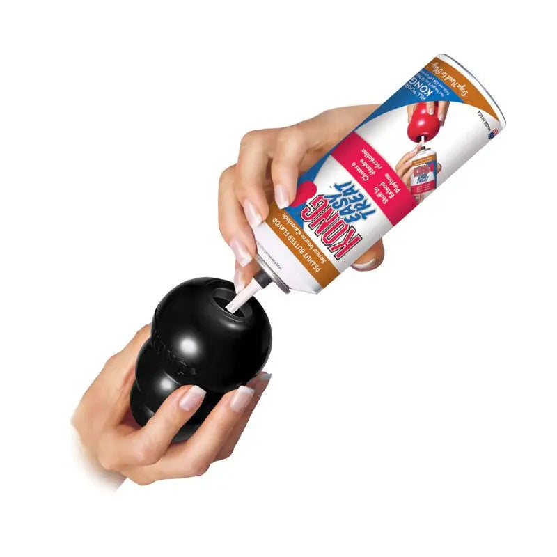 Hand filling a black Kong toy with dog treat spray for a fun pet snack.