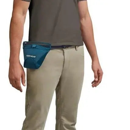 Man wearing a blue waist pack for outdoor activities, featuring a secure zipper closure.