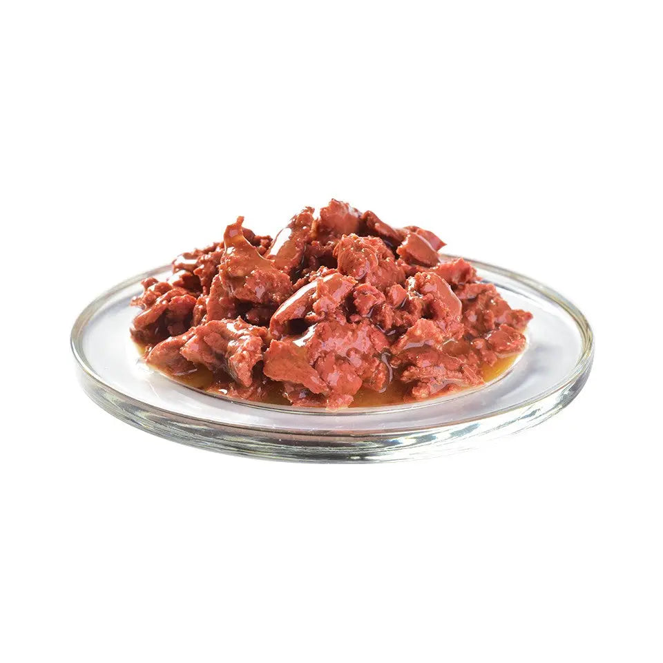 Wet cat food in a glass dish, featuring tender meat chunks in savory gravy.