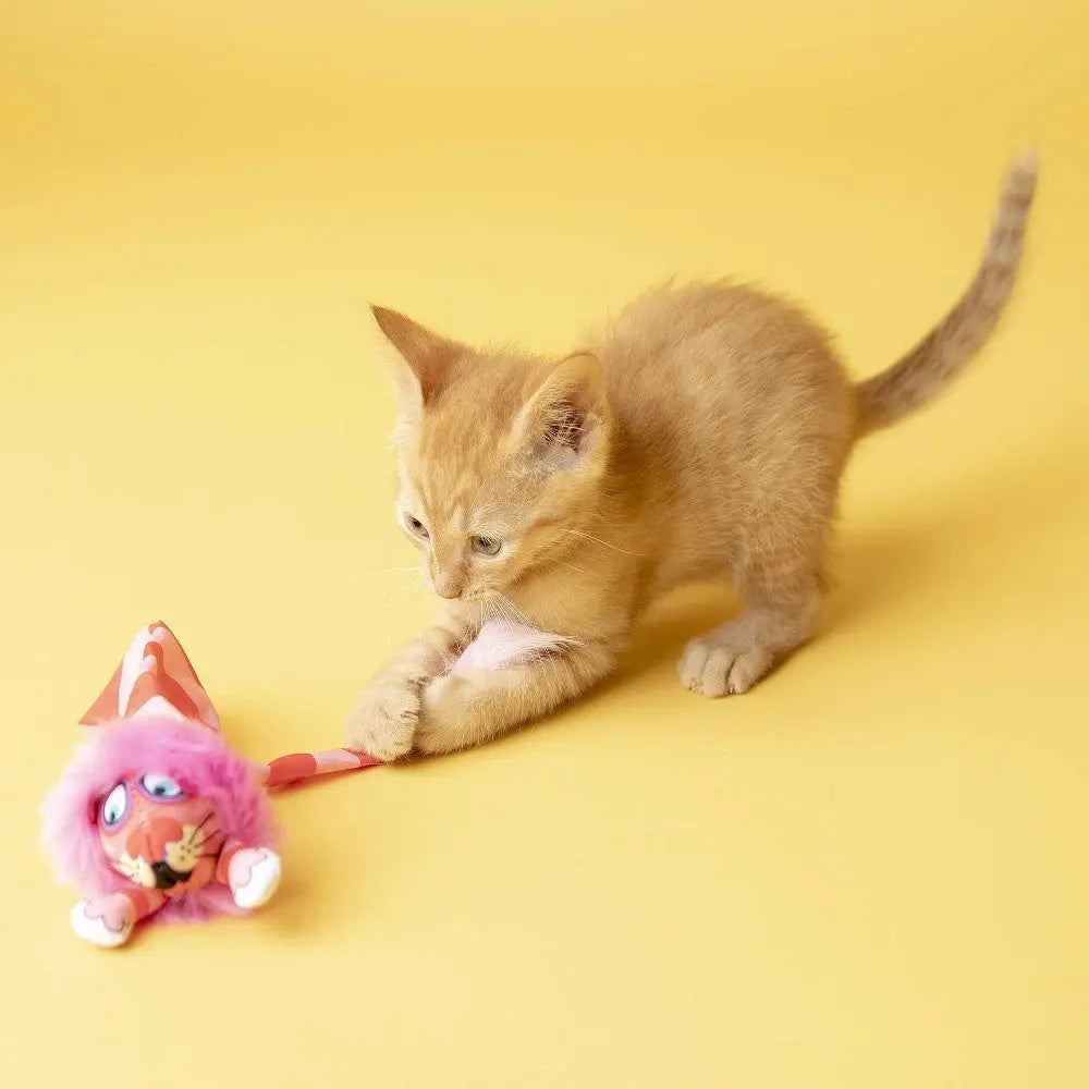 Playful orange kitten with a toy mouse on a bright yellow background.
