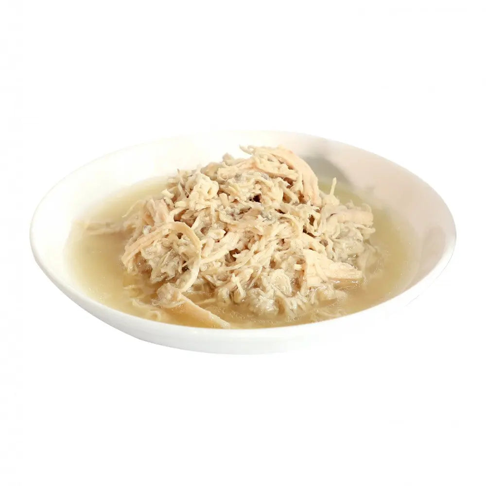 Shredded chicken in savory broth served in a white bowl, perfect for a comforting meal.