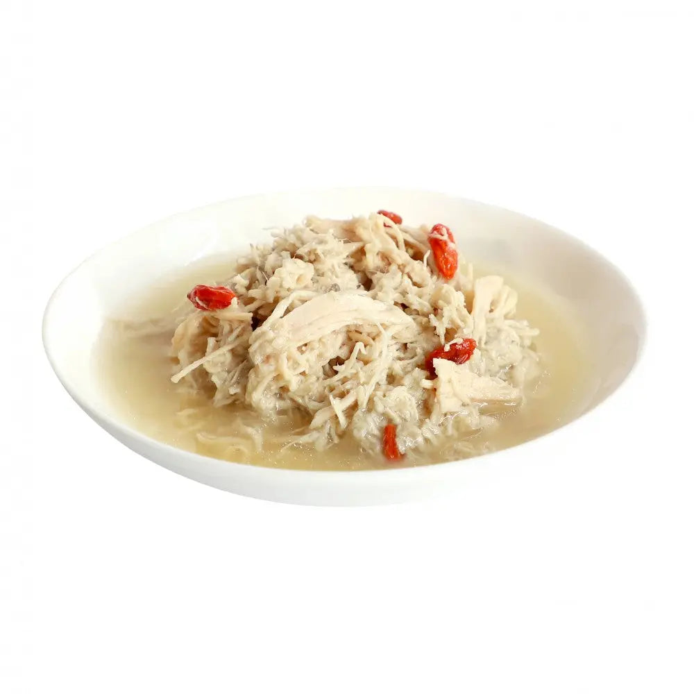 Delicious chicken soup with shredded meat and goji berries in a white bowl.