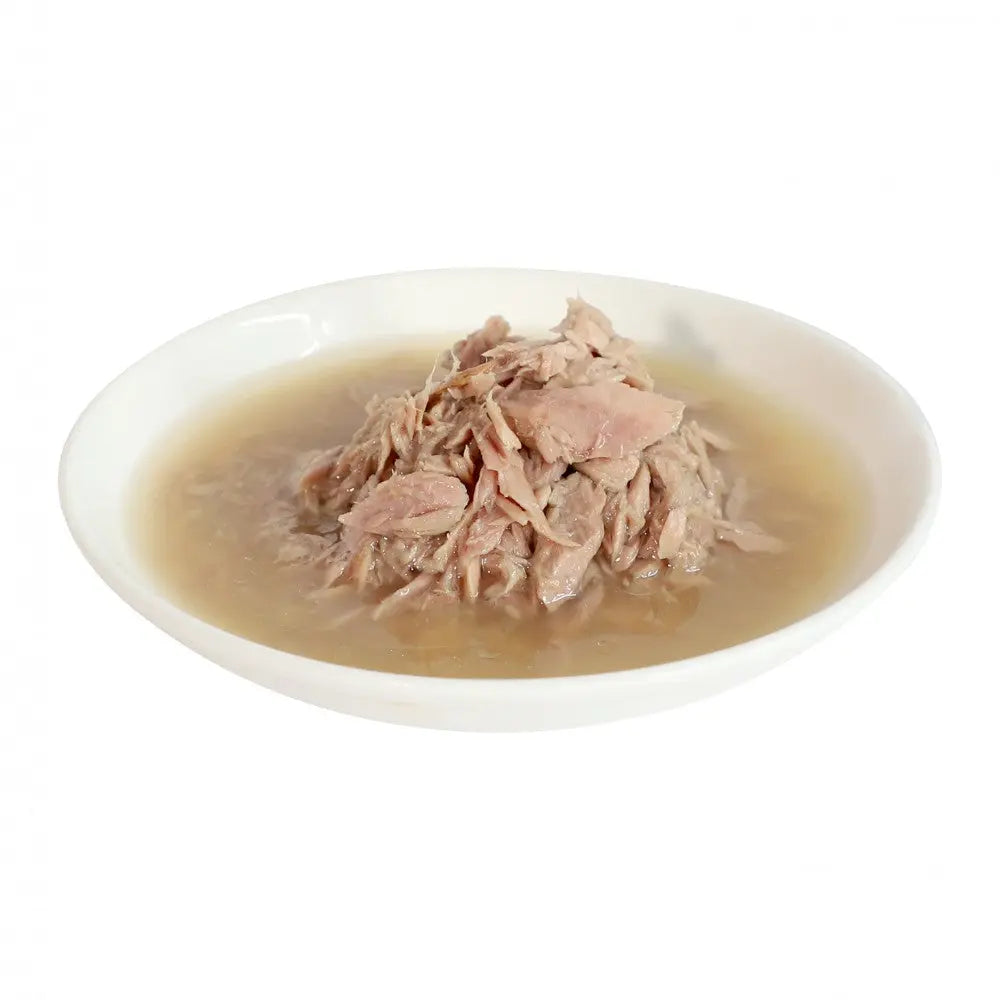 Canned tuna in broth served in a white bowl, showcasing tender, shredded fish.