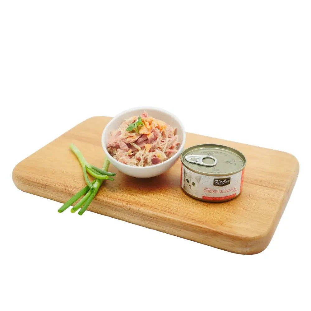 Canned chicken and salmon cat food served in a bowl with green onions on a wooden cutting board.
