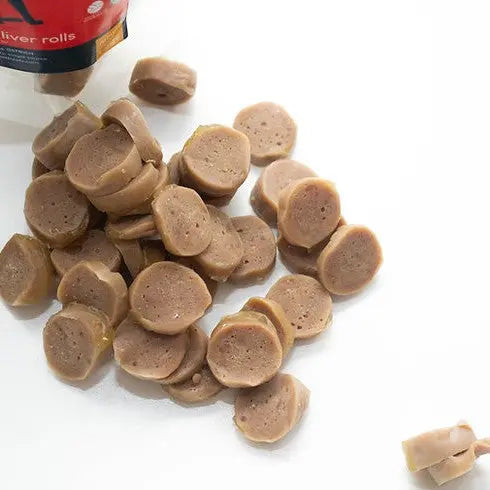 Sliced pet food rolls scattered on a white surface, ideal for training or rewarding pets.
