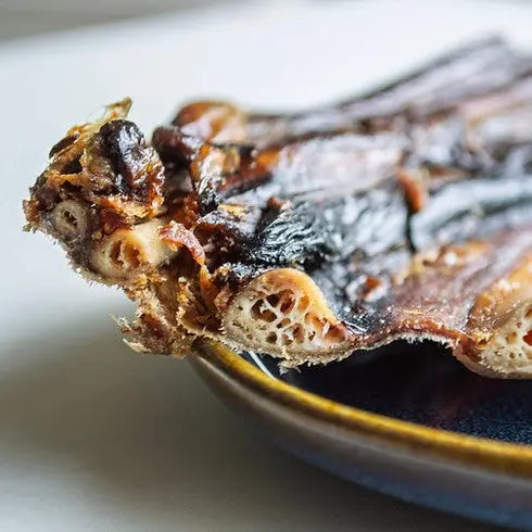 Dried fish snack on a plate, showcasing its crispy texture and rich flavor.