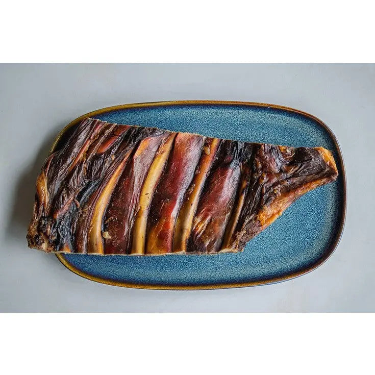 Dried beef jerky on a blue platter, showcasing rich textures and colors.