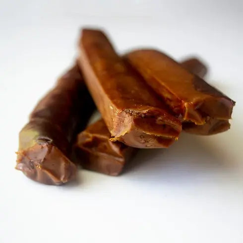 Beef sticks stacked on a white background, showcasing their savory, protein-rich snack appeal.