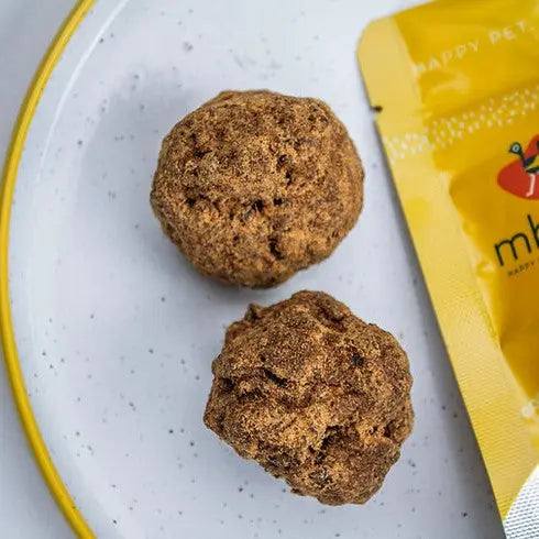 Pet food balls on a plate next to a colorful packaging pouch for a happy pet meal.