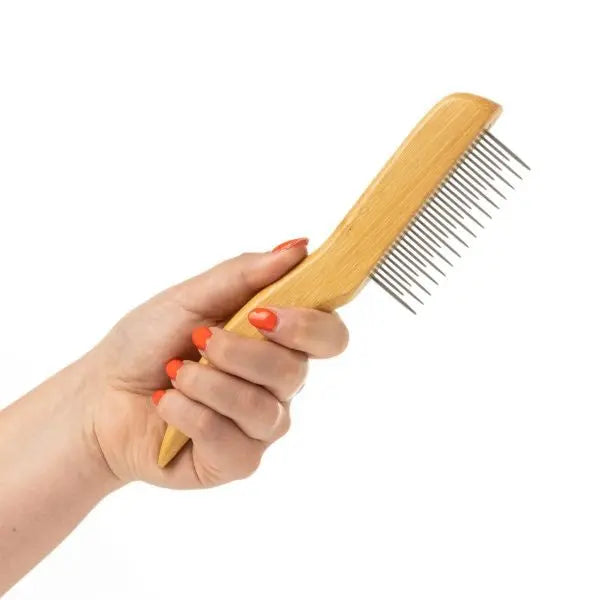 Hand holding a wooden hair comb with metal teeth for detangling and styling hair.