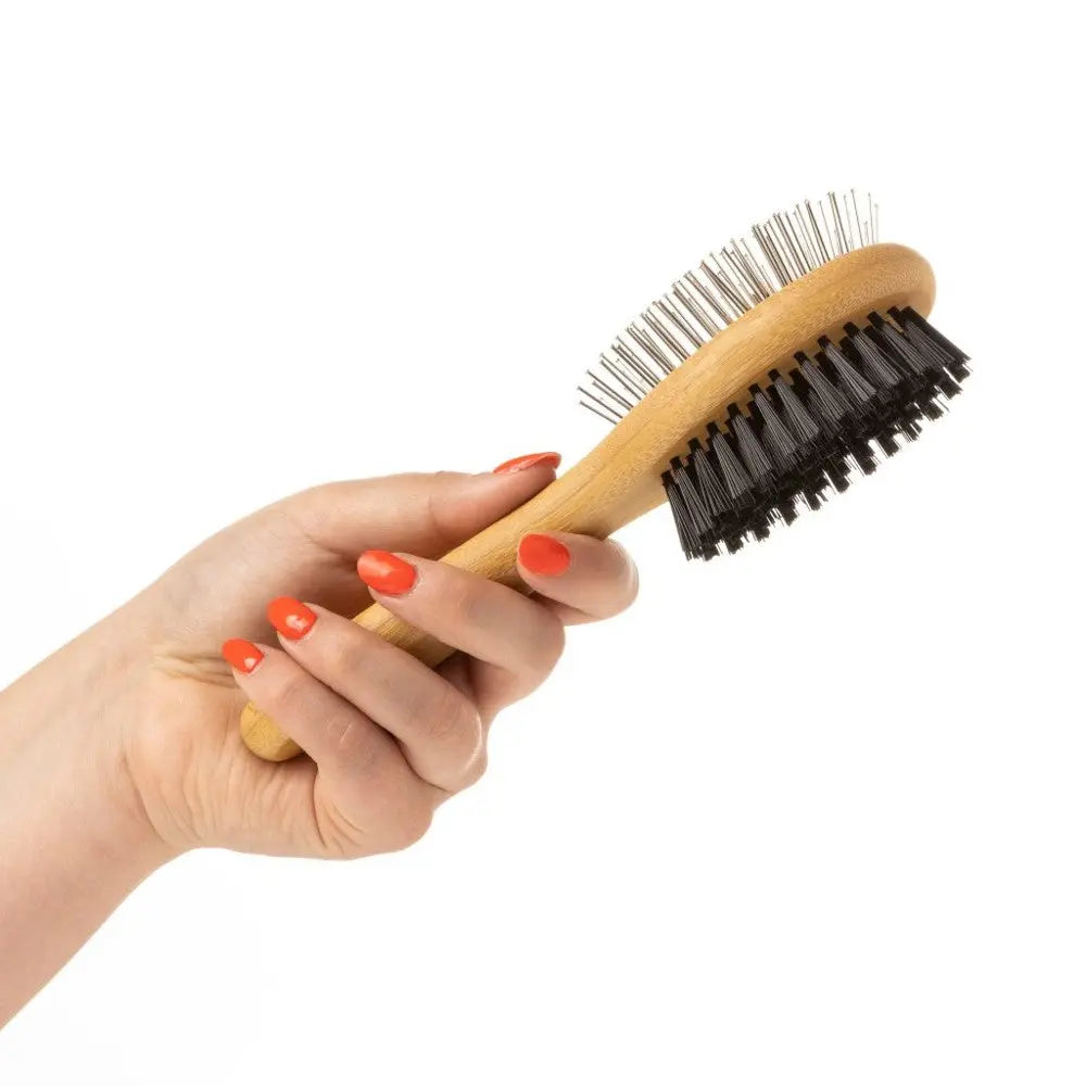 Hand holding a wooden hairbrush with mixed bristles for effective styling and detangling.