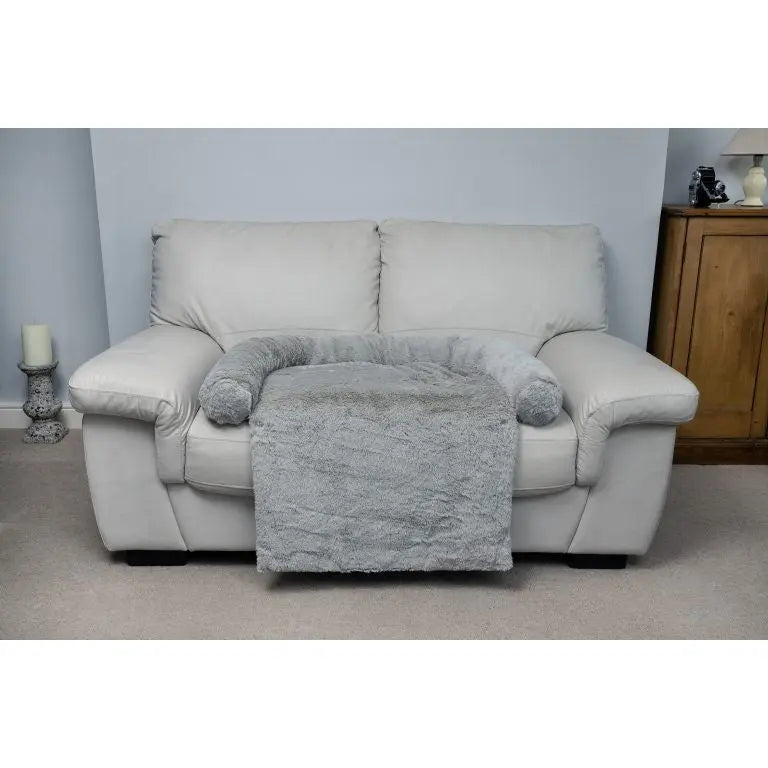 Cozy gray throw blanket and pillow on a light leather sofa in a stylish living room setting.