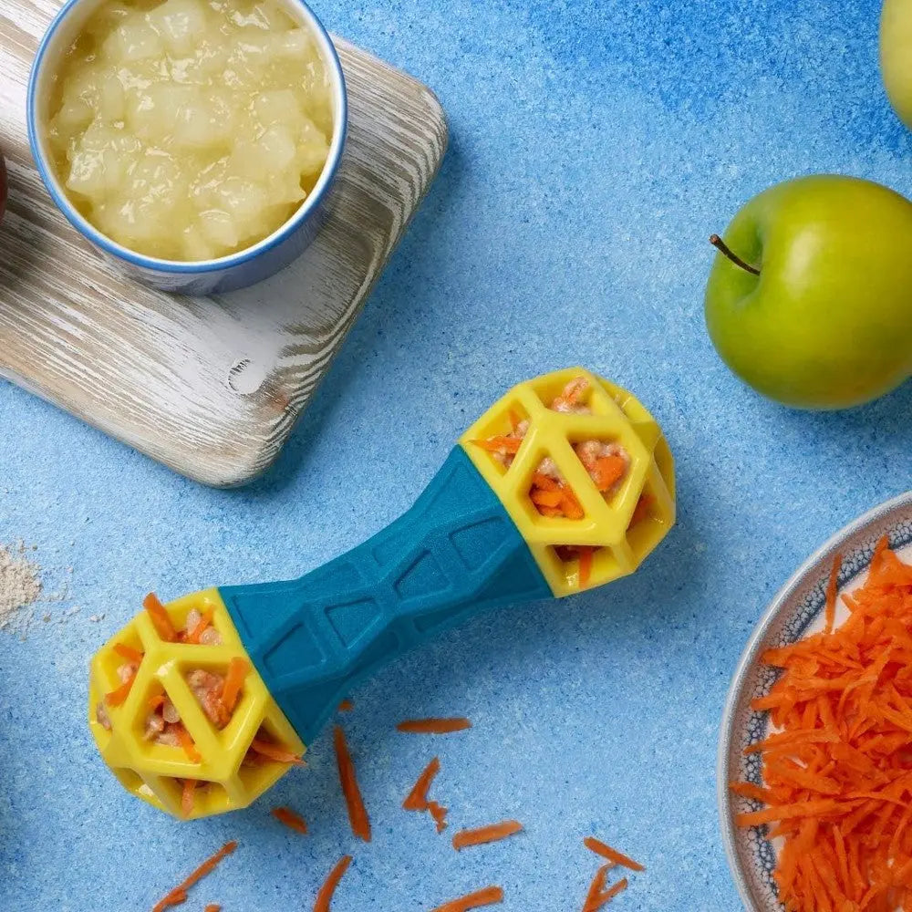 Colorful dog toy filled with carrots, apple slices, and applesauce on a blue background.