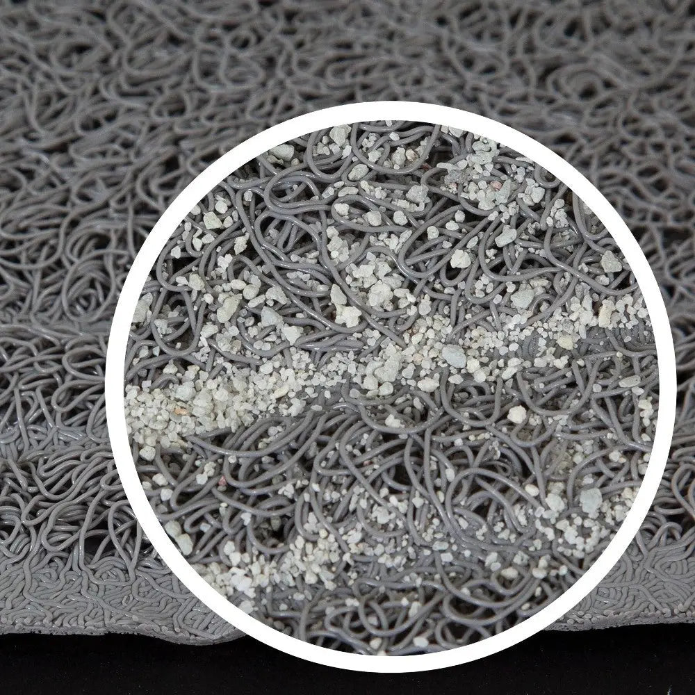 Close-up of textured gray rubber mat with intricate loops and scattered white particles for grip and durability.
