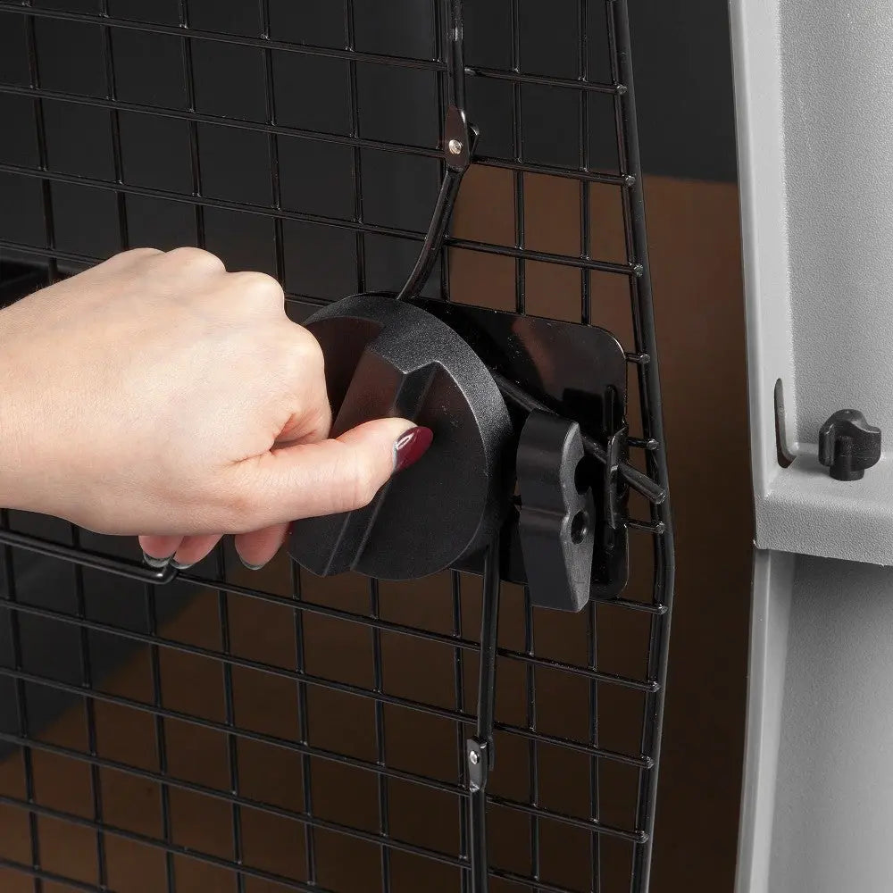 Hand securing a pet crate latch for safety and convenience.