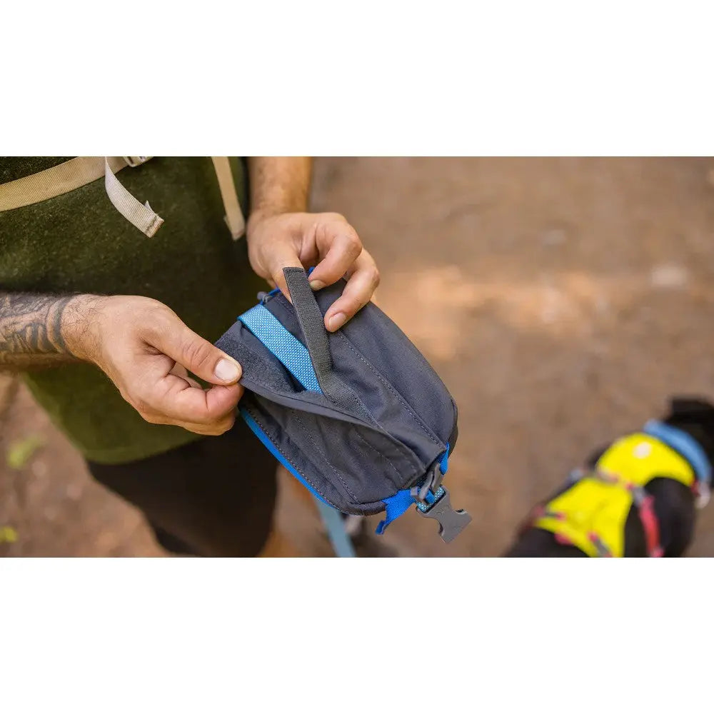 Person adjusting a dog backpack strap while preparing for an outdoor adventure.