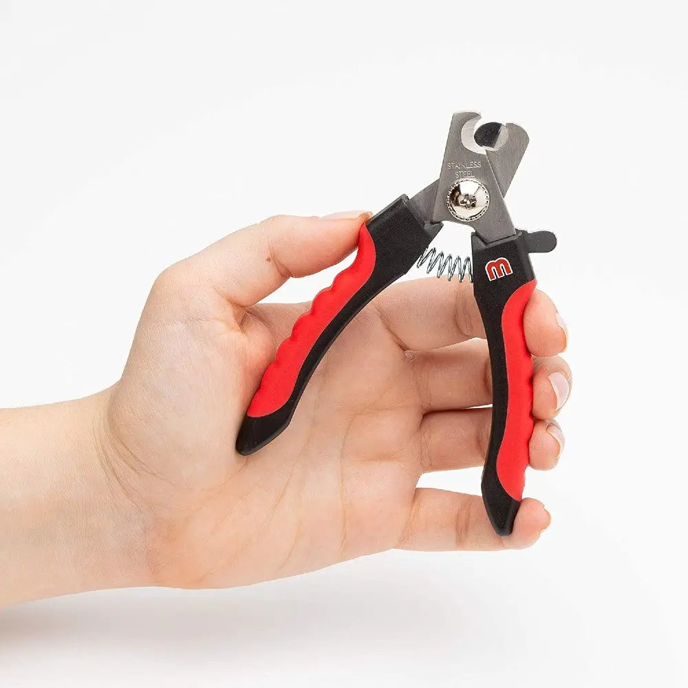 Hand holding a red and black pet nail clipper with stainless steel blades.