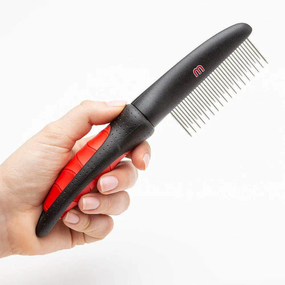 Hand holding a black and red grooming comb for pets, designed for effective detangling.
