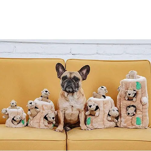 French Bulldog with plush toy stack on a couch, showcasing playful pet accessories.