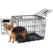 Chihuahua standing beside a black wire dog crate with an open door for easy access.