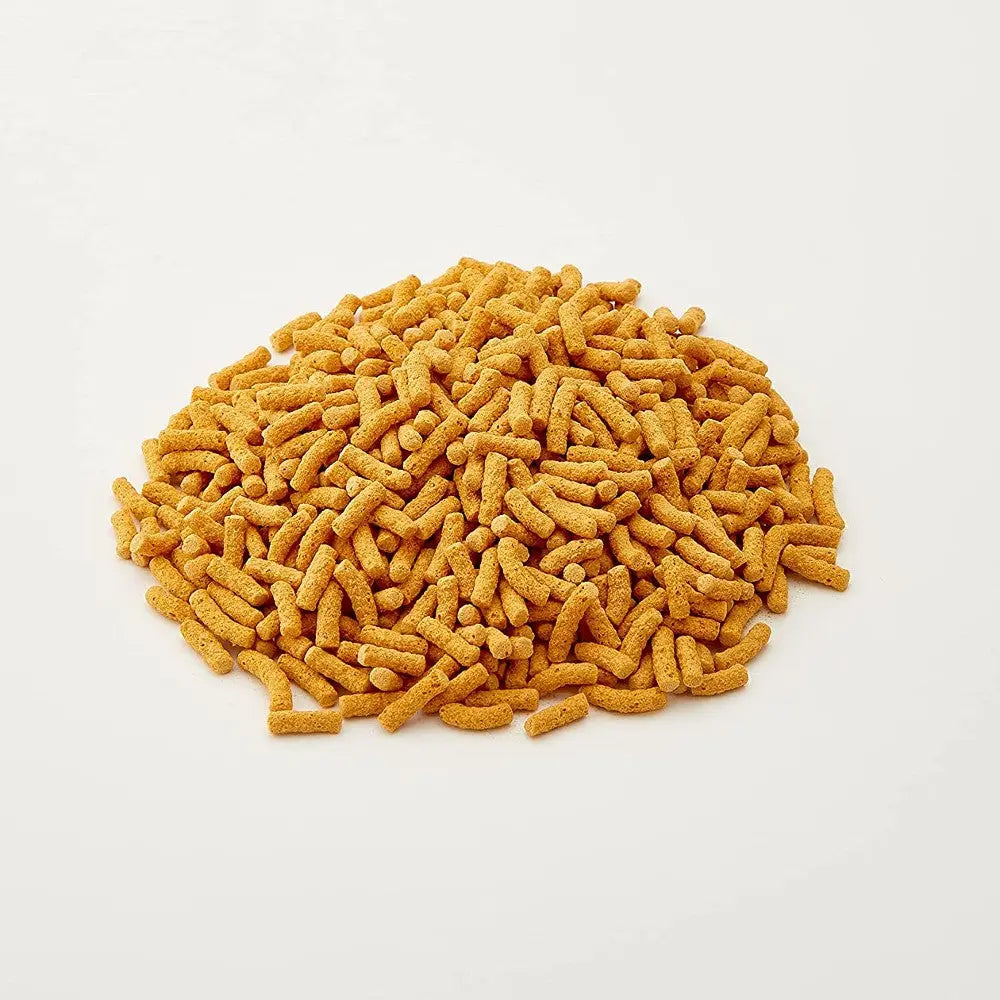 Golden pet food kibble scattered on a white background, showcasing its crunchy texture and shape.