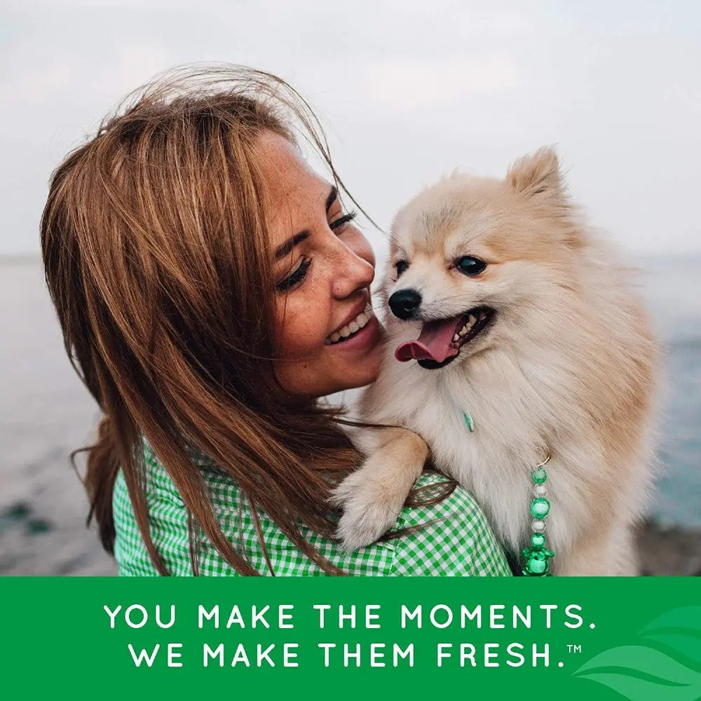 Woman smiling while holding a happy Pomeranian dog by the water, capturing a joyful moment together.